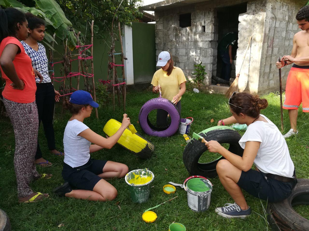 Projects Abroad Childcare volunteers paint tyres outside a kindergarten for a multi-sensory garden in Sri Lanka. Childcare volunteers in Sri Lanka paint tyres for a multi-sensory garden at their Childcare placement.